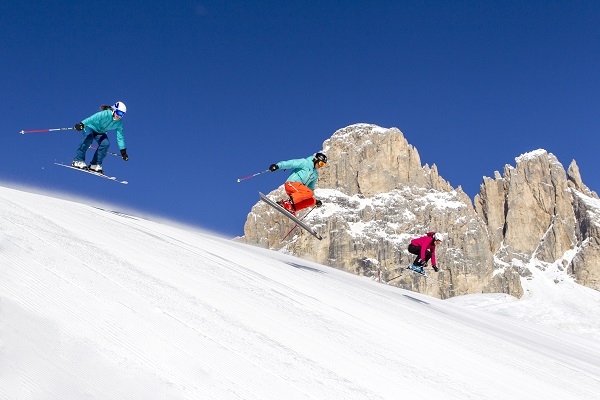 Tre personer som åker skidor i en skidbacke i Dolomiterna, Italien.